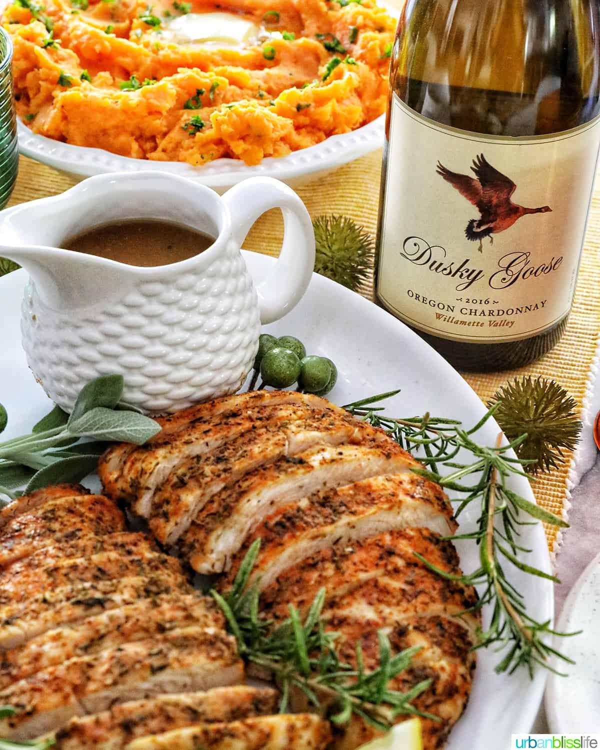 plate of sliced turkey tenderloin with sides of gravy and sweet potatoes and a bottle of wine.