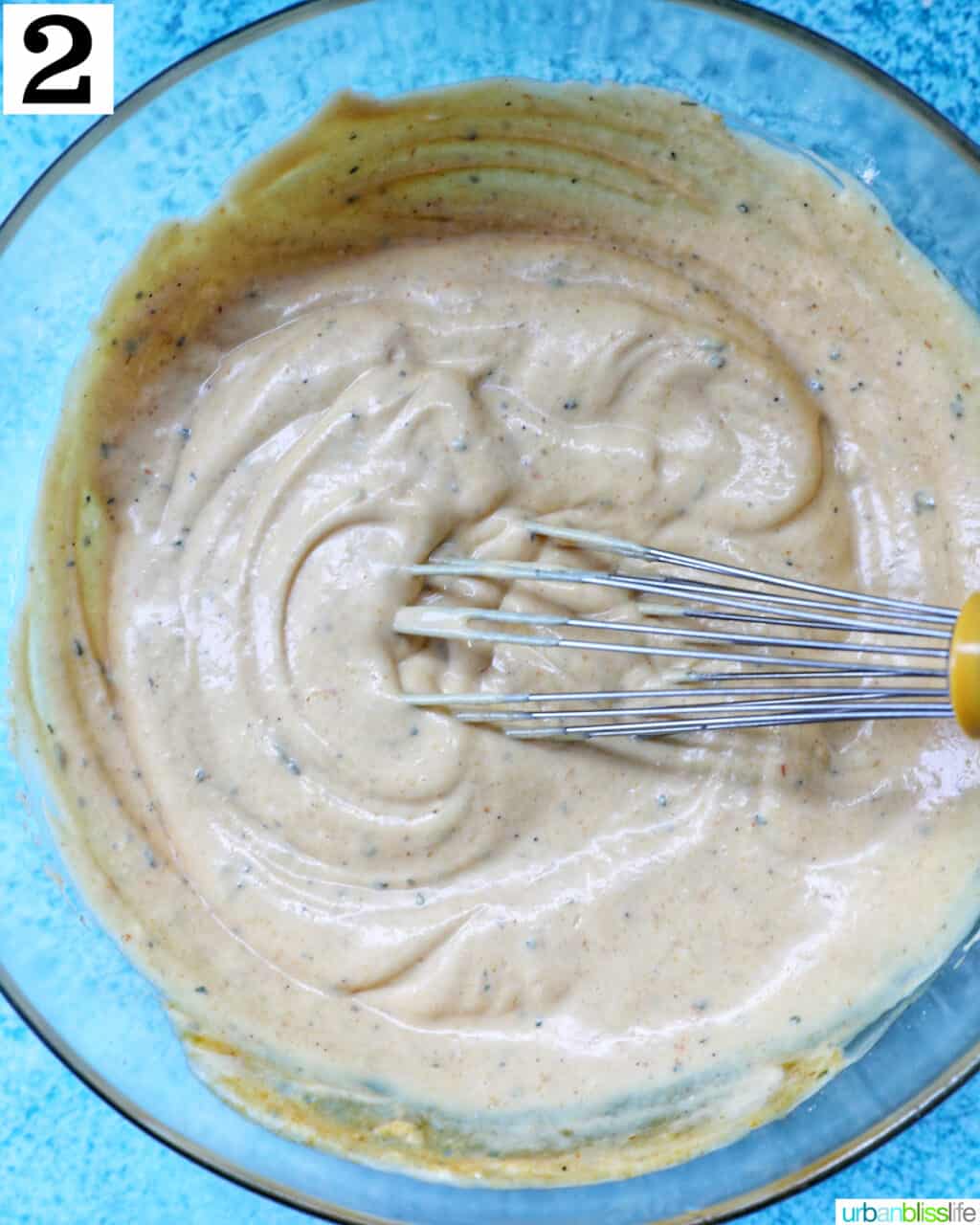 whisk in a bowl of bowl of buffalo ranch sauce.