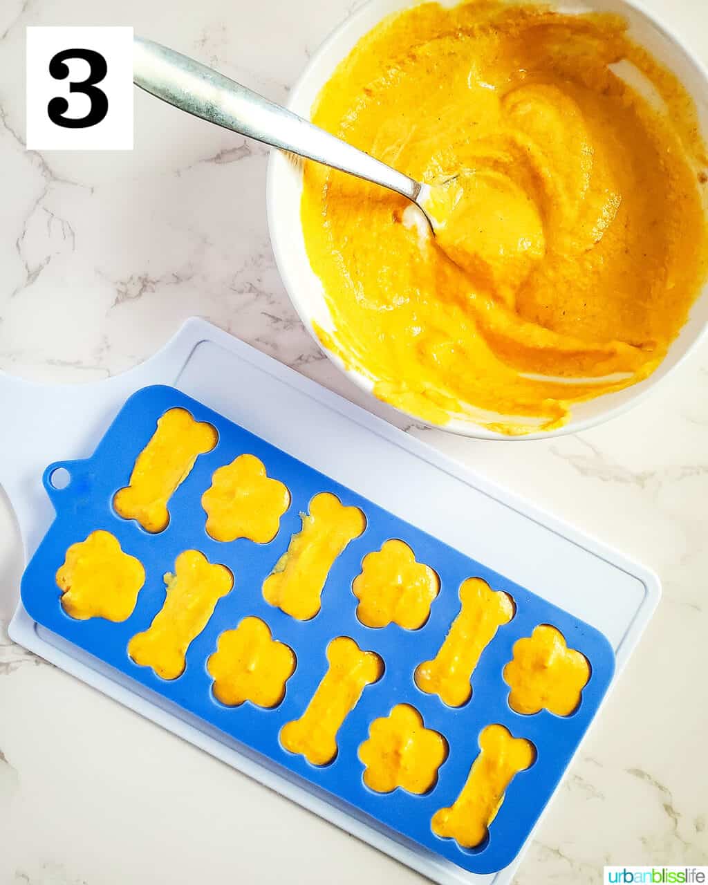 dog treat silicone molds filled with pumpkin yogurt dog treat batter next to a bowl of batter.