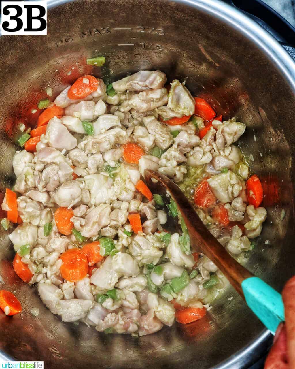 wooden spoon stirring cooked chicken pieces with vegetables in an instant pot.