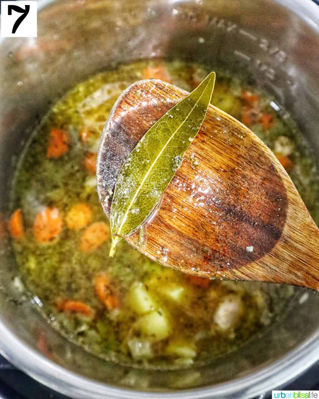 wooden spoon removing the bay leaf from instant pot chicken stew.