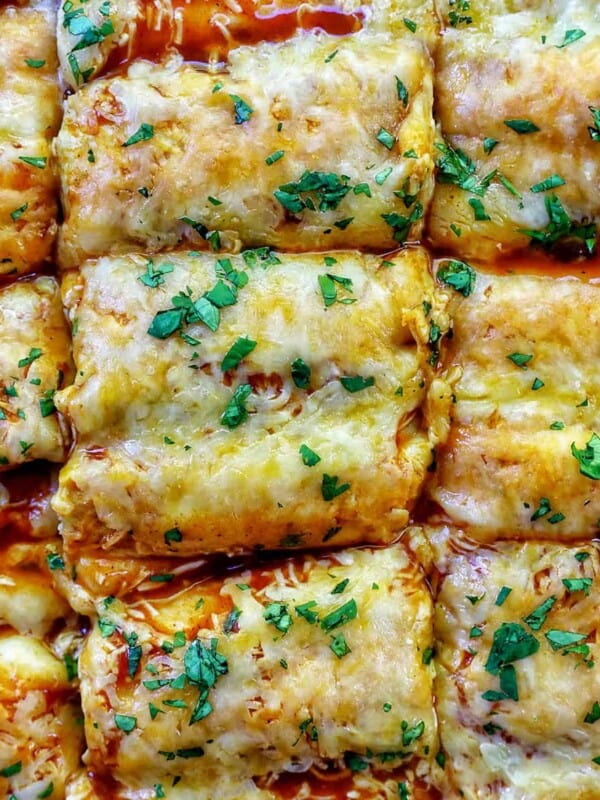 cheesy turkey enchiladas casserole sliced into squares with fresh herbs as garnish.