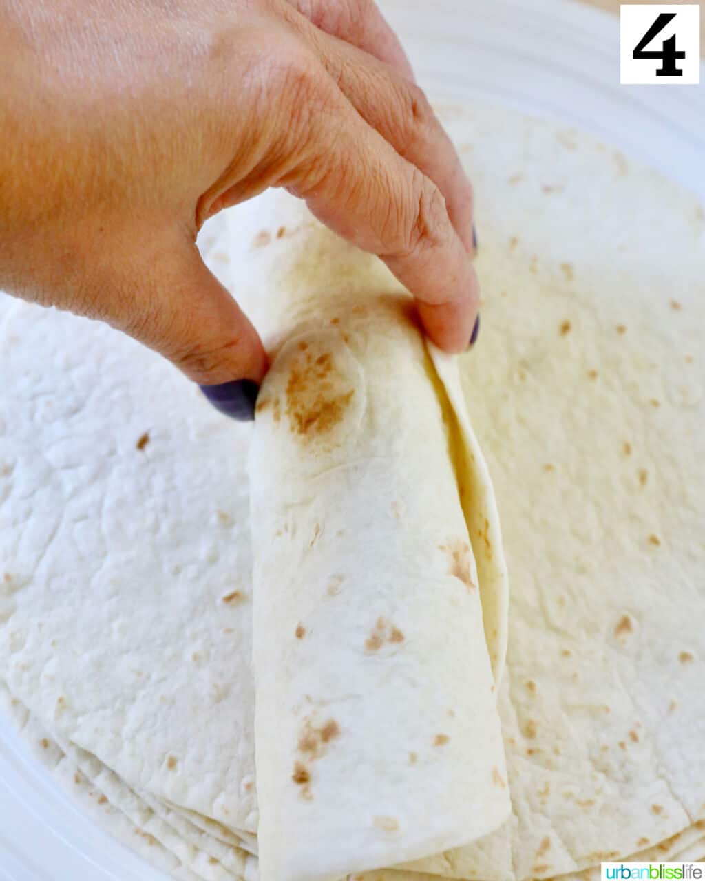 hand rolling a flour tortilla up.