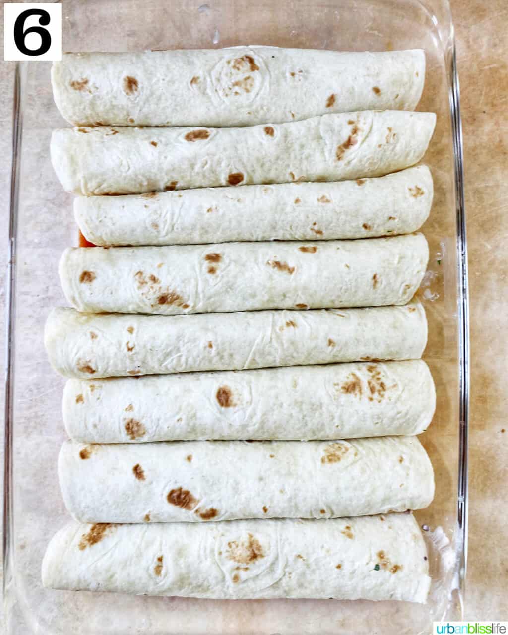 rolled flour tortilla enchiladas in a glass baking dish.