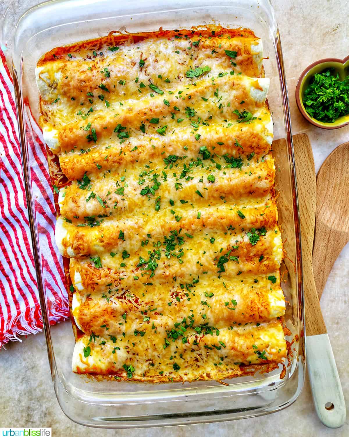 cheesy turkey enchiladas casserole in a glass baking dish with red and white striped towel.