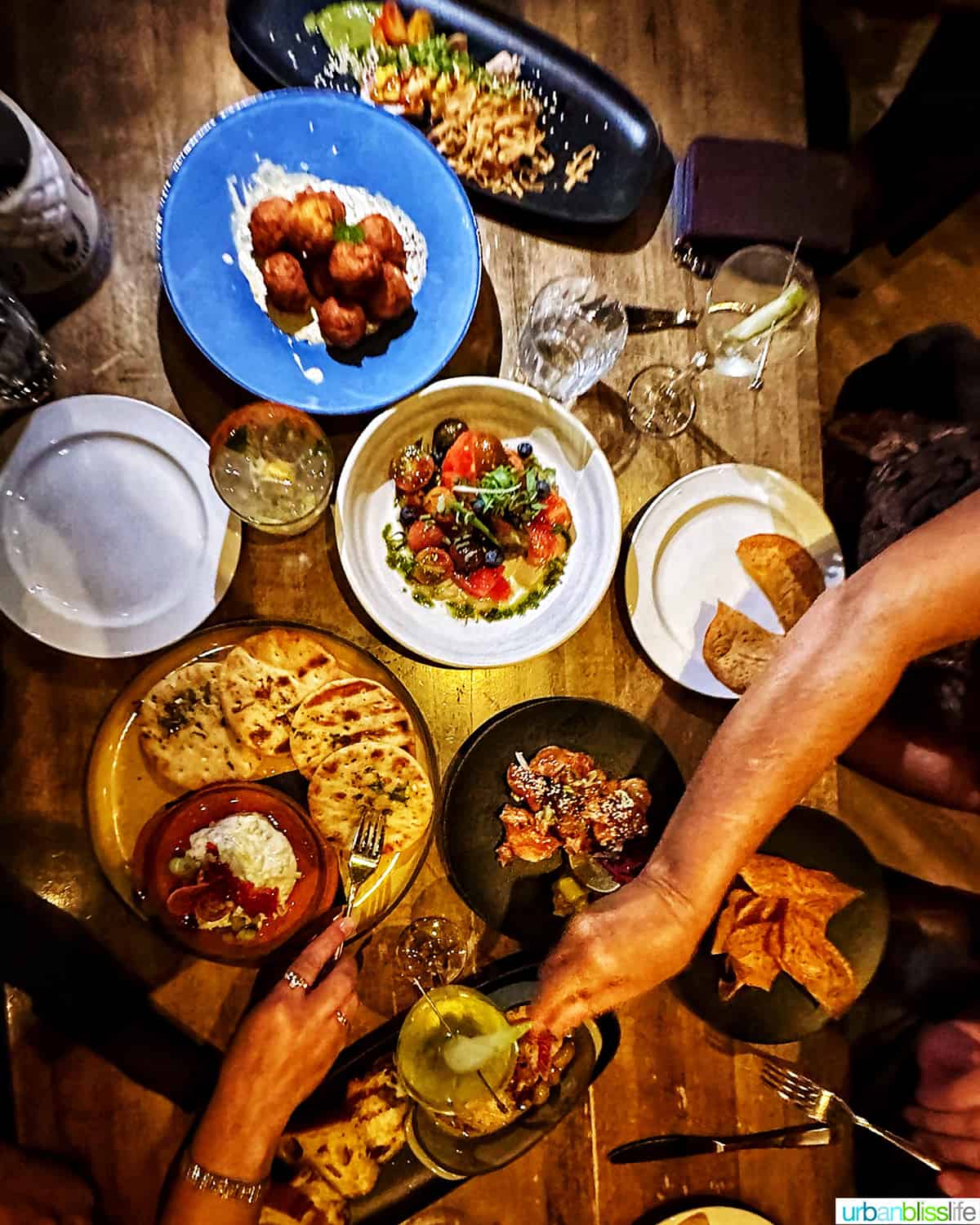 overhead photo of a wood table full of plates and hands getting food at the Raven Room in Whistler BC Canada.