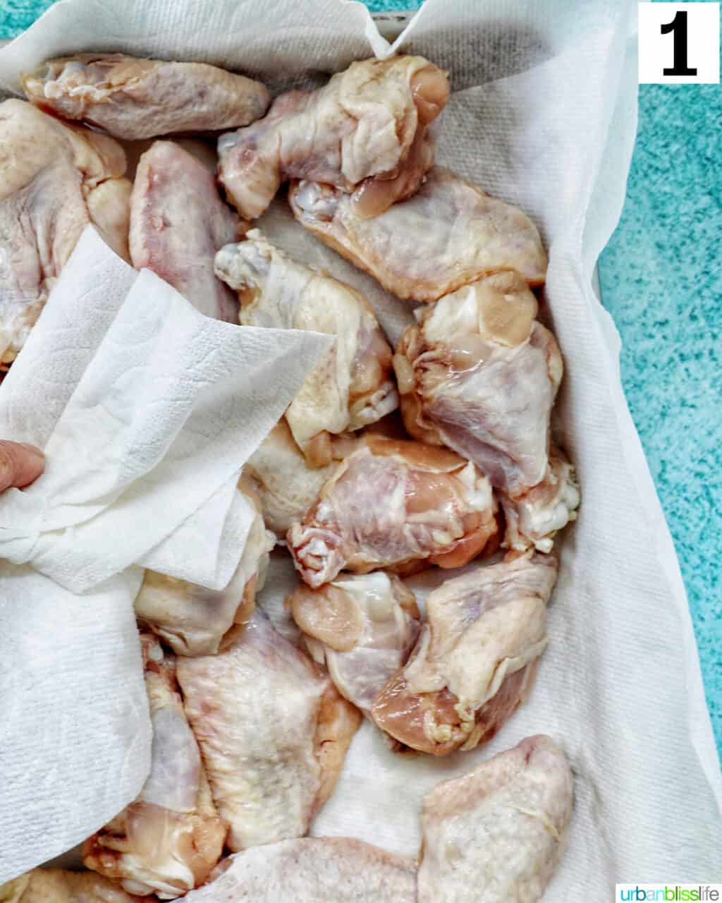 dabbing raw chicken wings with a paper towel to dry before baking.