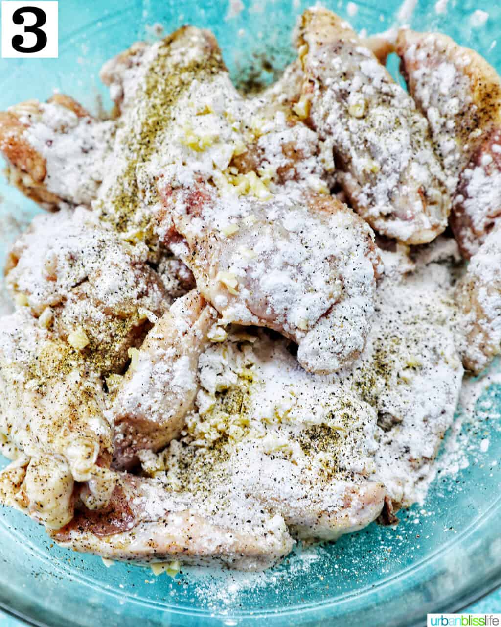 seasoned chicken wings in a large glass bowl.