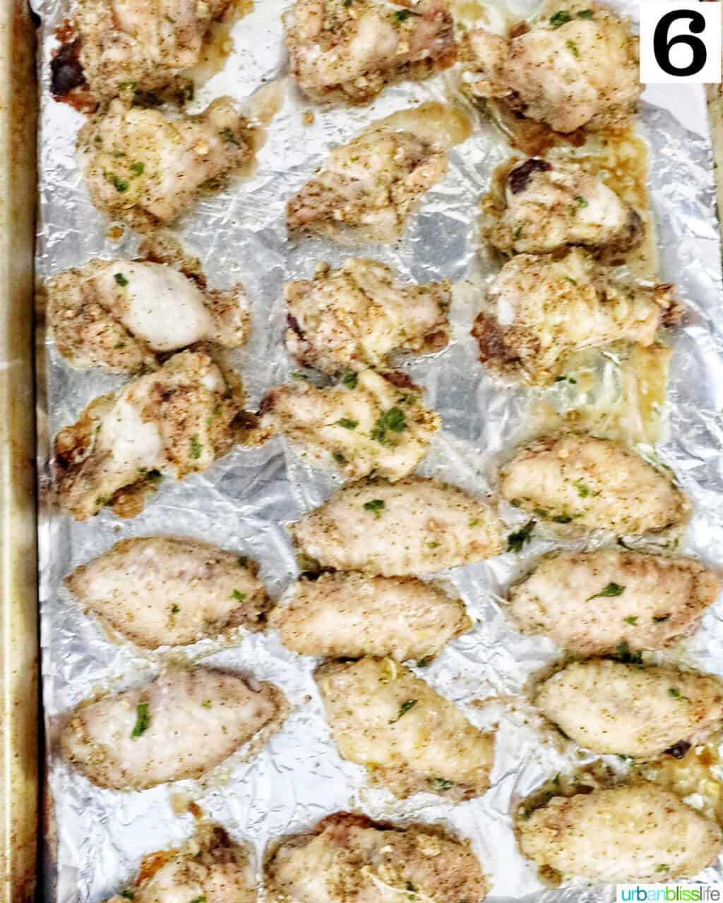 chicken wings in rows on aluminum foil on a baking sheet.