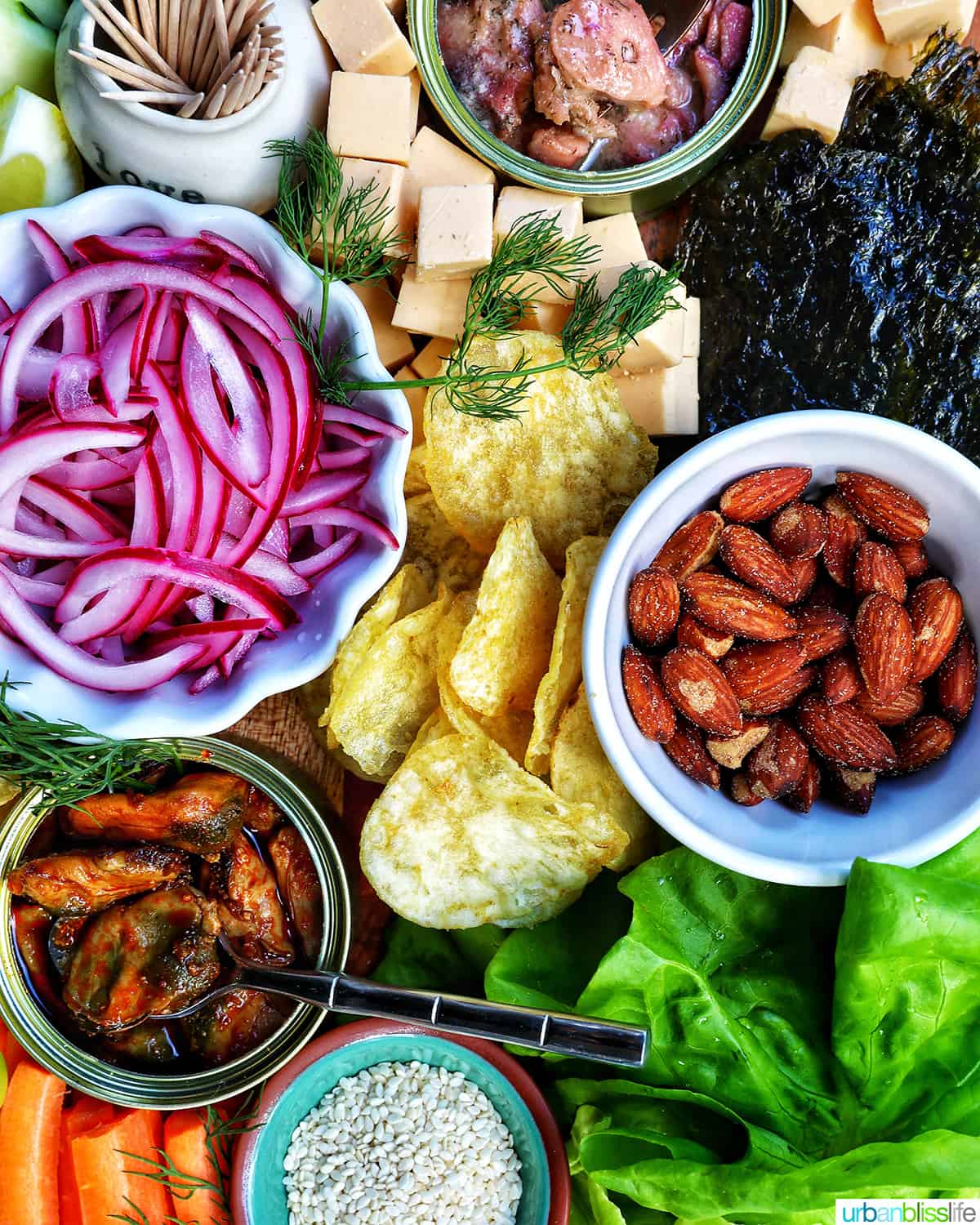 seacuterie board with tinned fish, fruits, vegetables, chips, crackers, and garnishes.