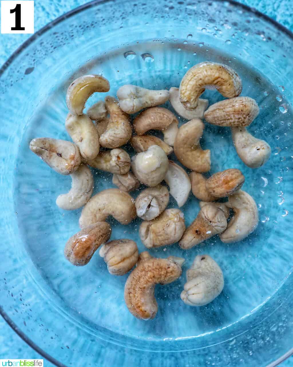 cashews soaking in water in a glass bowl.