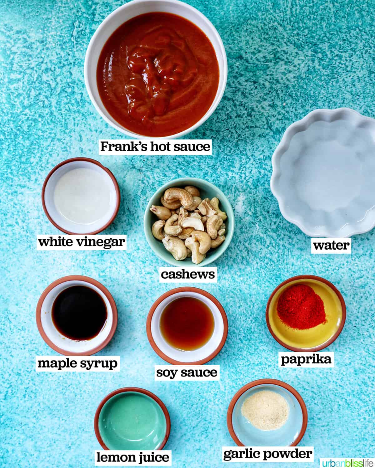 bowls of ingredients to make Vegan Buffalo Sauce on a blue table.