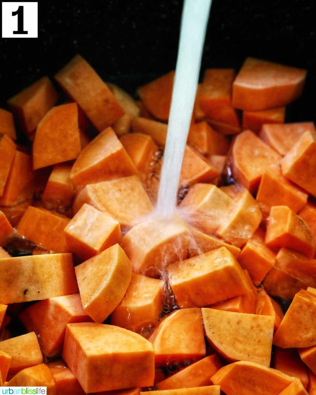 water pouring over a large pot of chopped sweet potatoes.