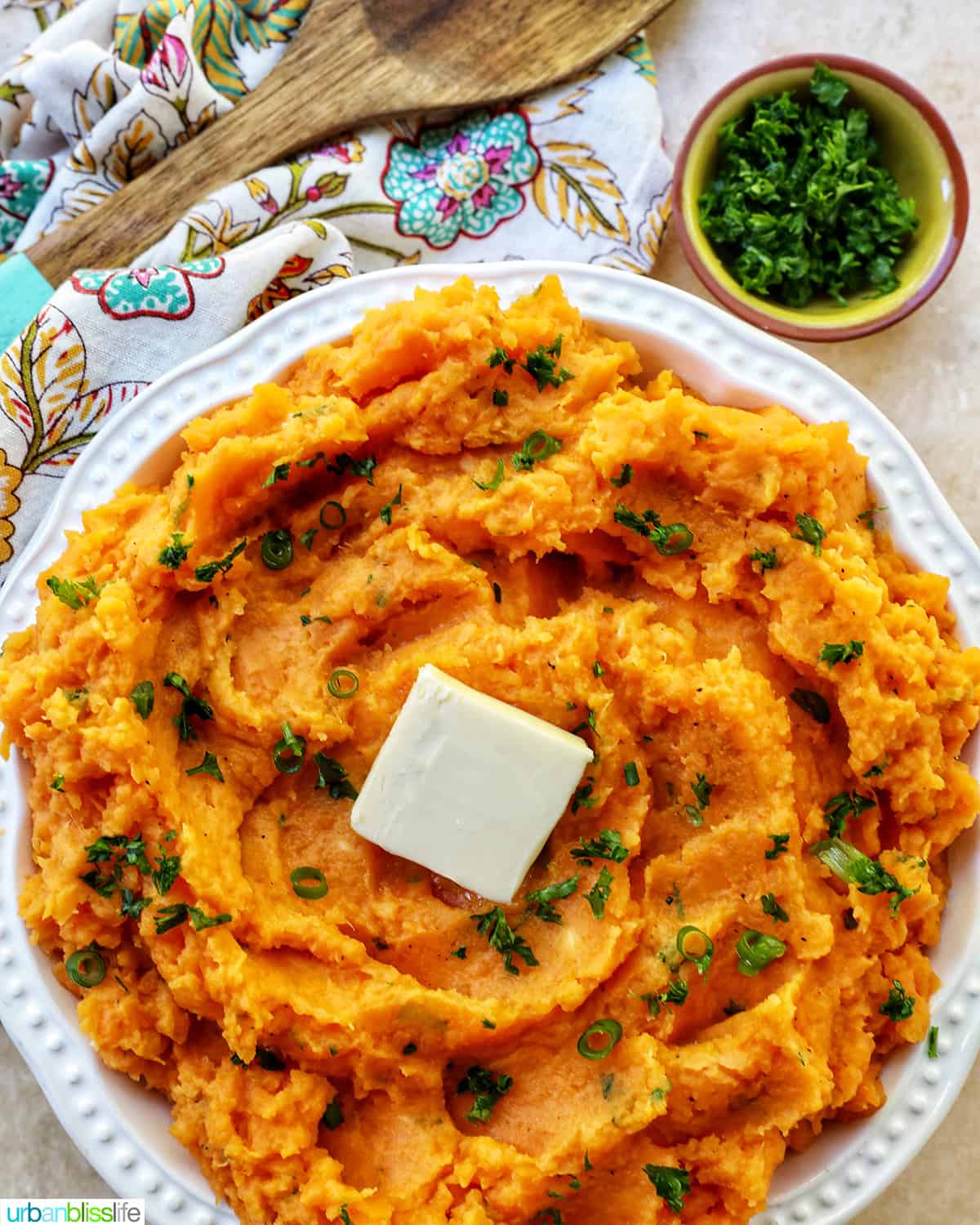 bowl of whipped sweet potatoes and a pat of butter with fresh herbs.