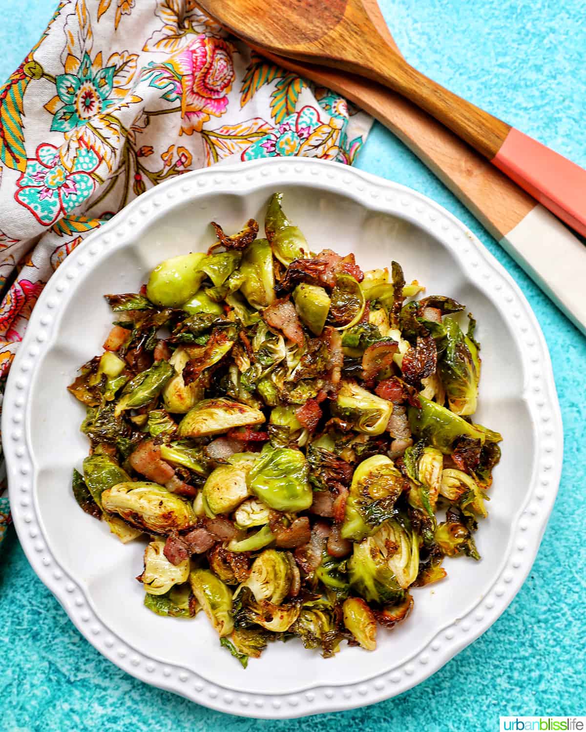 bowl of brussels sprouts with bacon and set of wooden serving spoons.