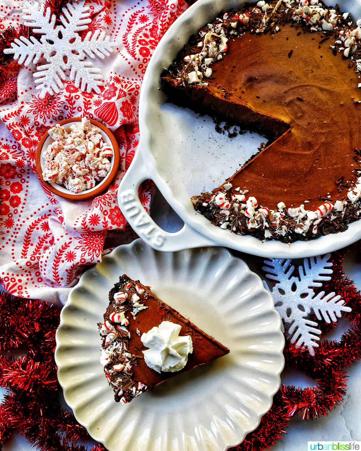 slice of Chocolate Peppermint Pie on a scalloped plate next to the full pie and a bowl of pepperming candies.