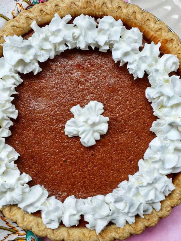 cinnamon pie with whipped cream on a pink background.