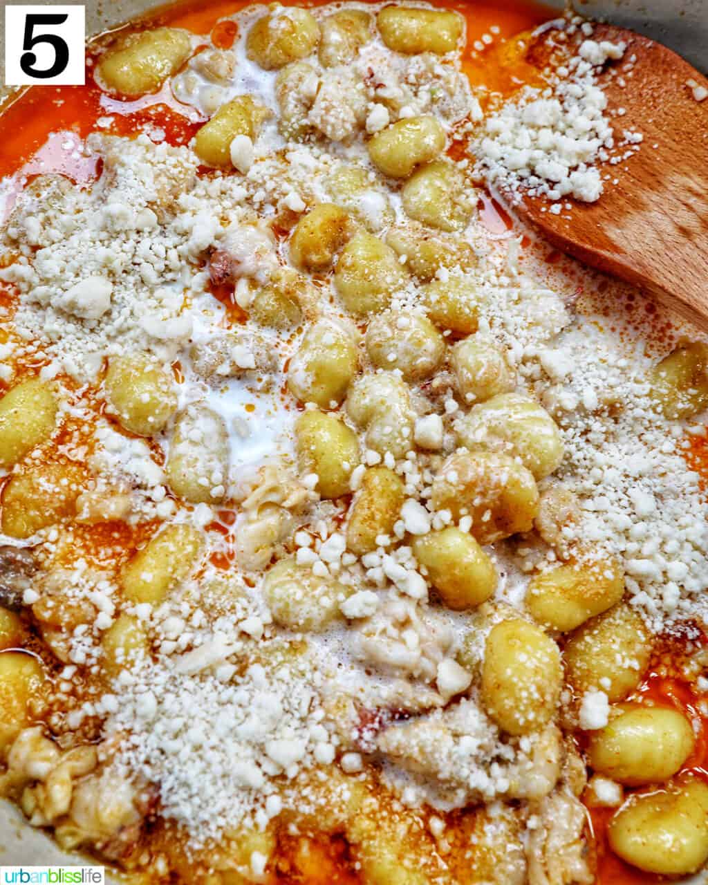 adding parmesan cheese to gnocchi in a skillet.
