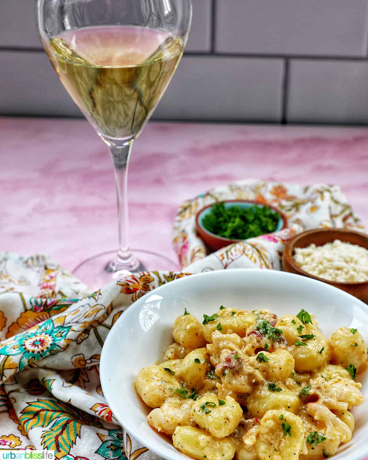 glass of white wine with a bowl of lobster gnocchi.