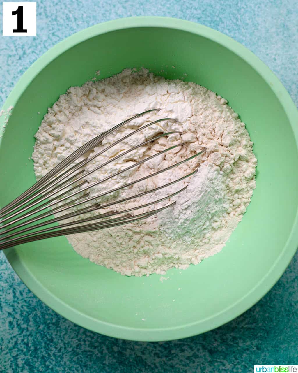 flour and whisk in a green bowl.