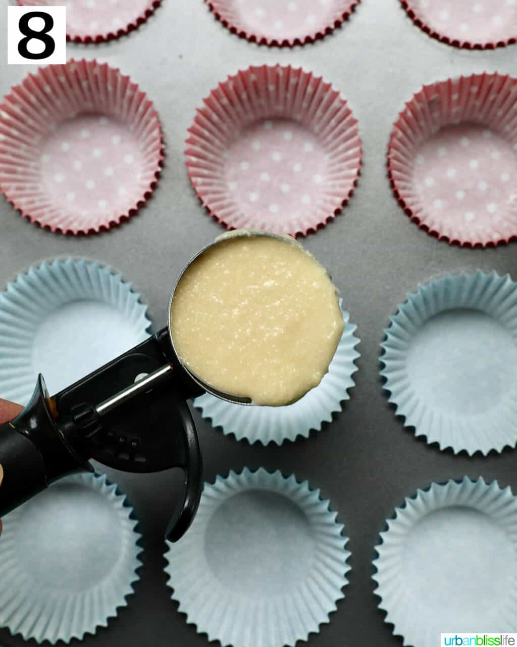 scoop of cupcake batter over cupcake liners in muffin tin.