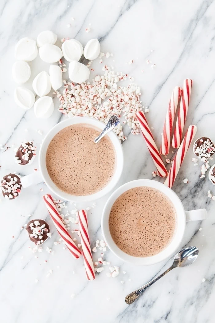 two cups of spiked peppermint mocha hot chocolate with marshmallows and candy canes.