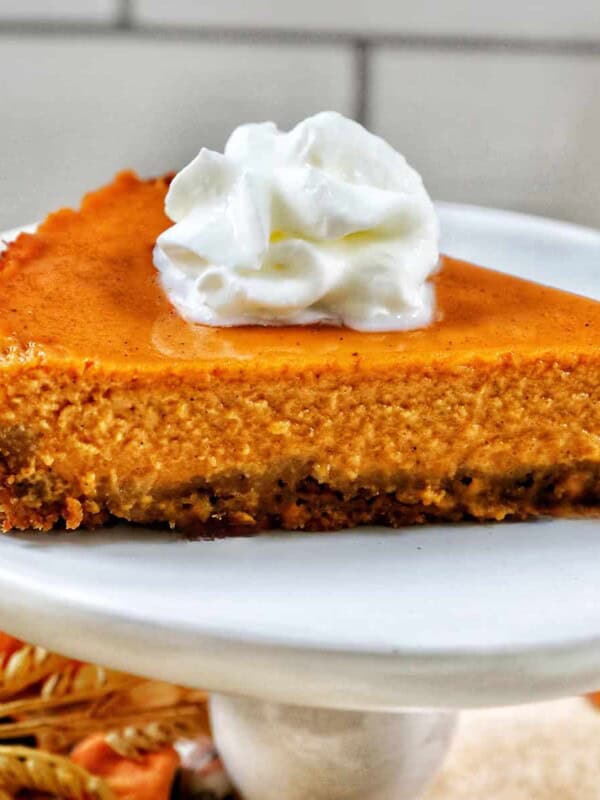 slice of sweet potato pie with whipped cream on a white plate.