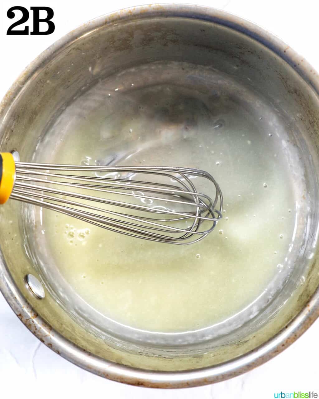whisk mixing melted white chocolate and cream in a saucepan.