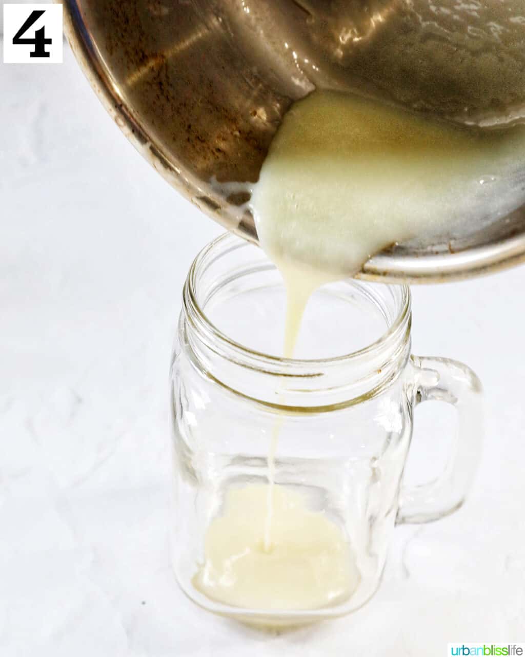 Pouring melted white chocolate into a clear glass mug.