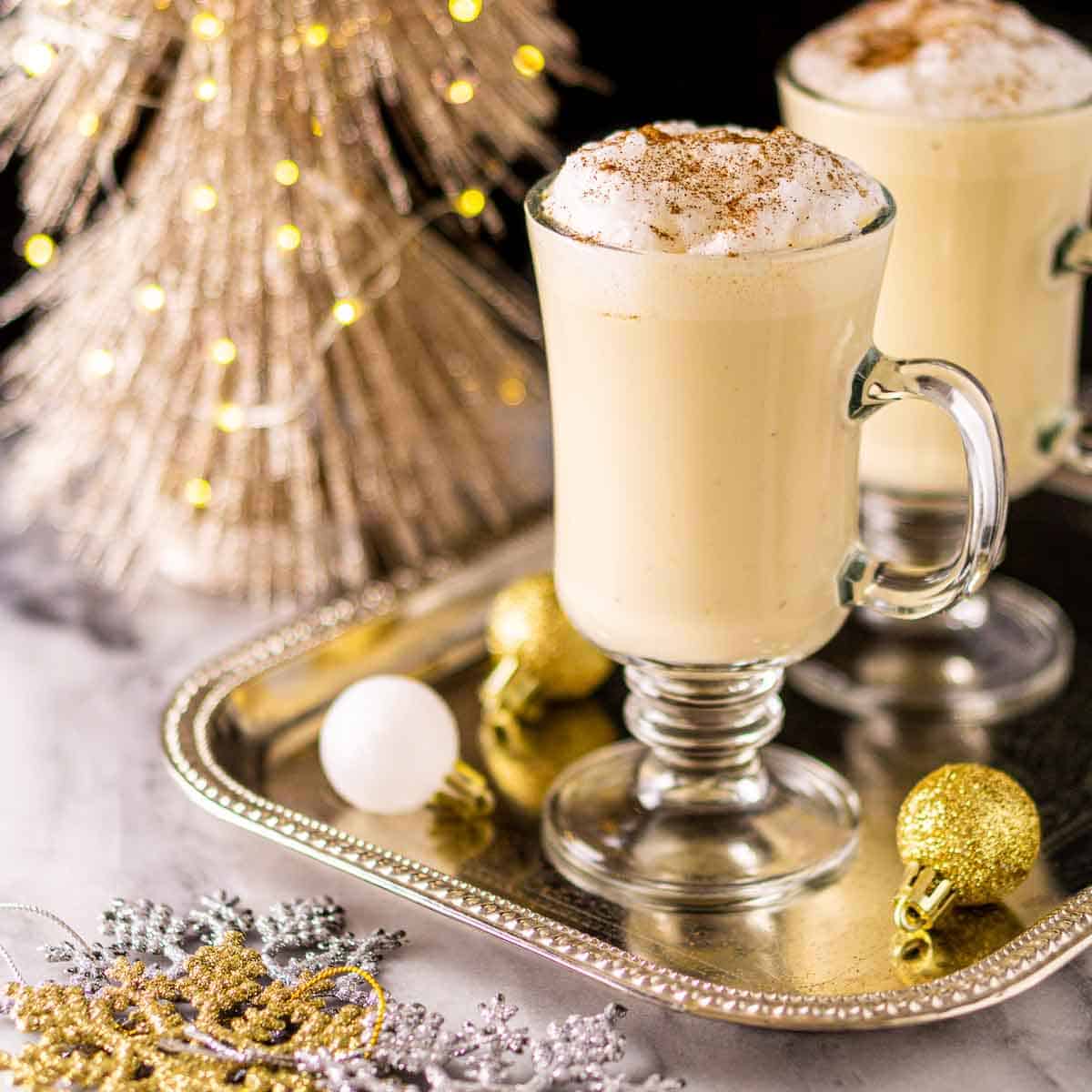 glasses of Baileys egg nog on a serving tray with Christmas ornaments.