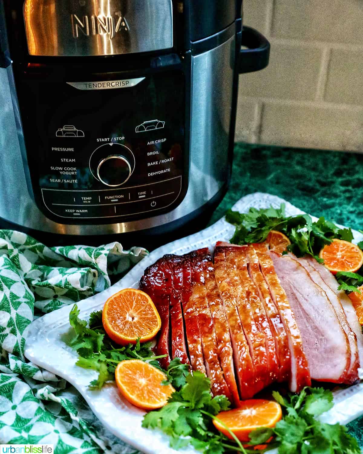 Ninja Foodi air fryer with an air fryer ham plated in front of it.