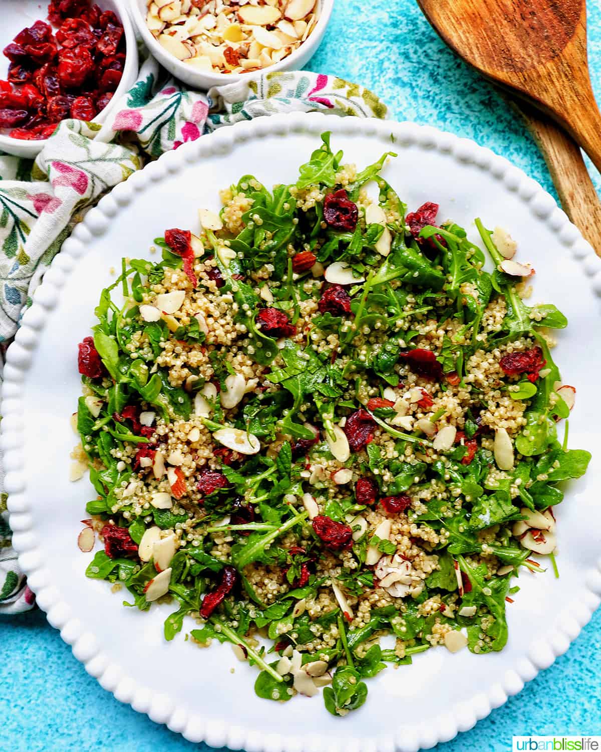 white bowl with arugula and quinoa salad with sliced almonds and dried cranberries.