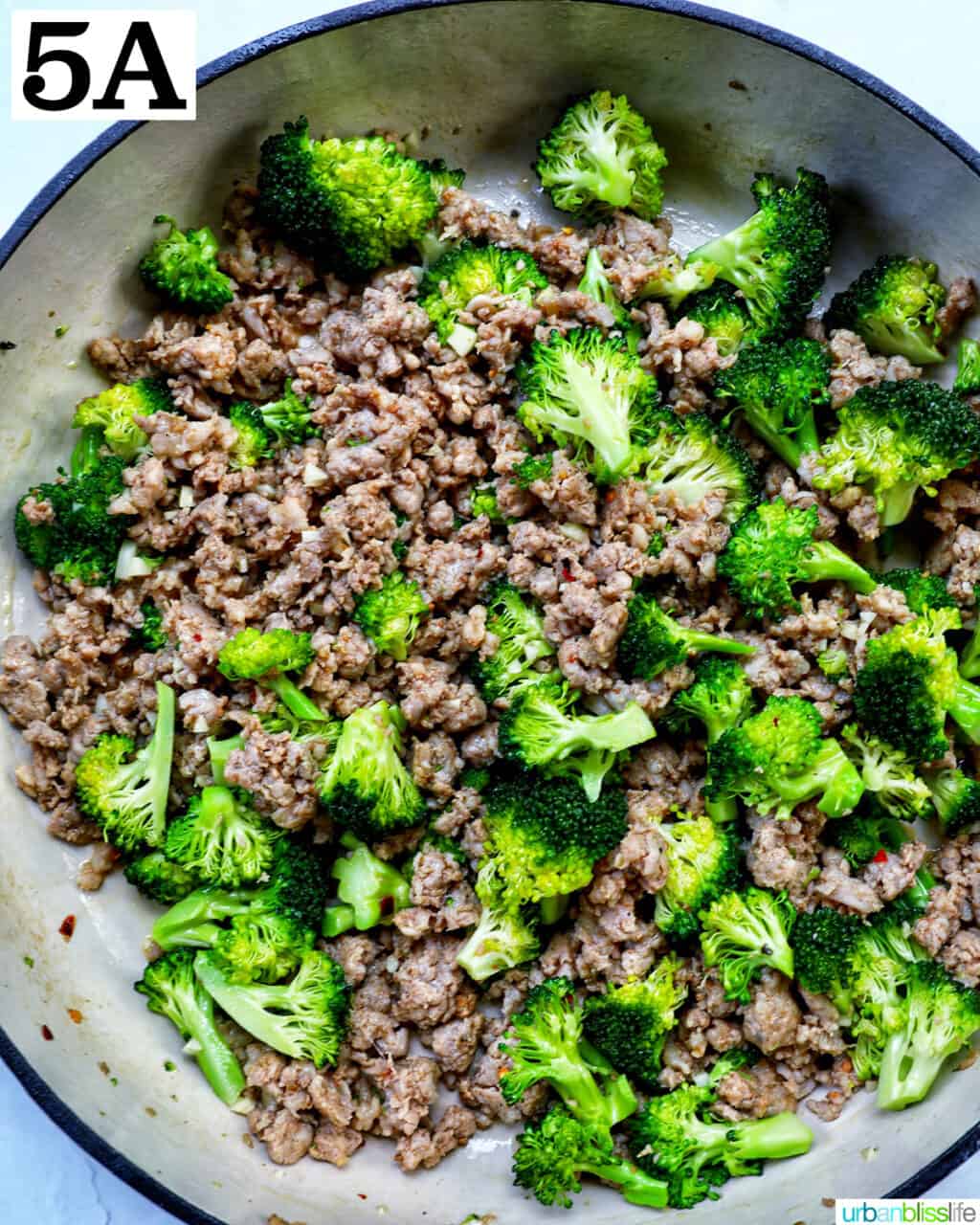 chopped broccoli and Italian sausage cooking in a large skillet.