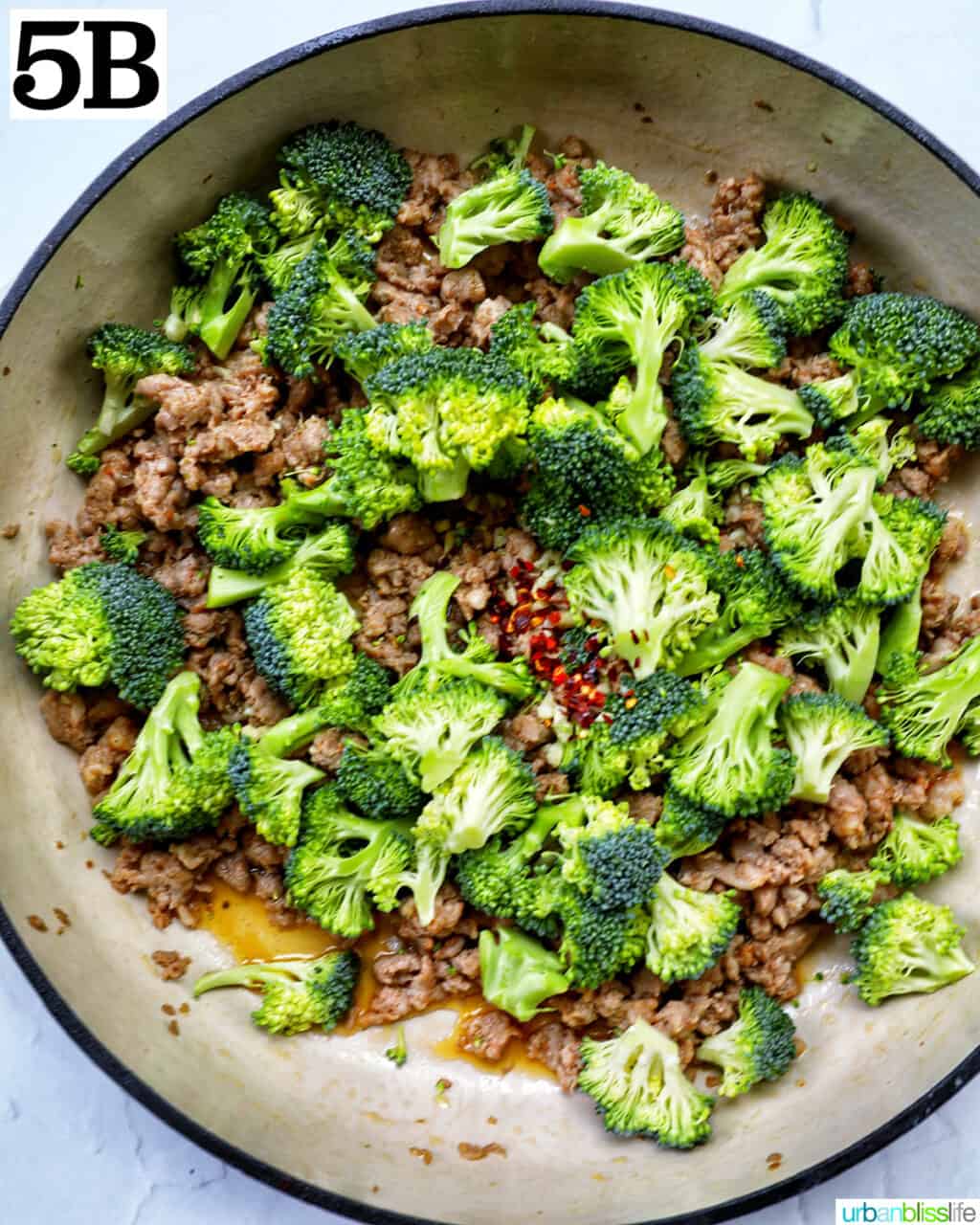 red pepper flakes added to broccoli and Italian sausage cooking in a large skillet.