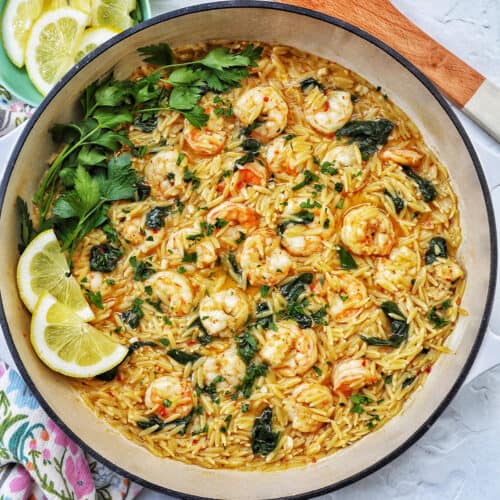 Skillet with shrimp scampi and orzo, lemons, and parsley.