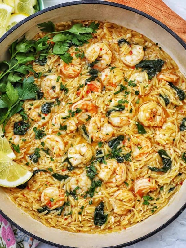 Skillet with shrimp scampi and orzo, lemons, and parsley.