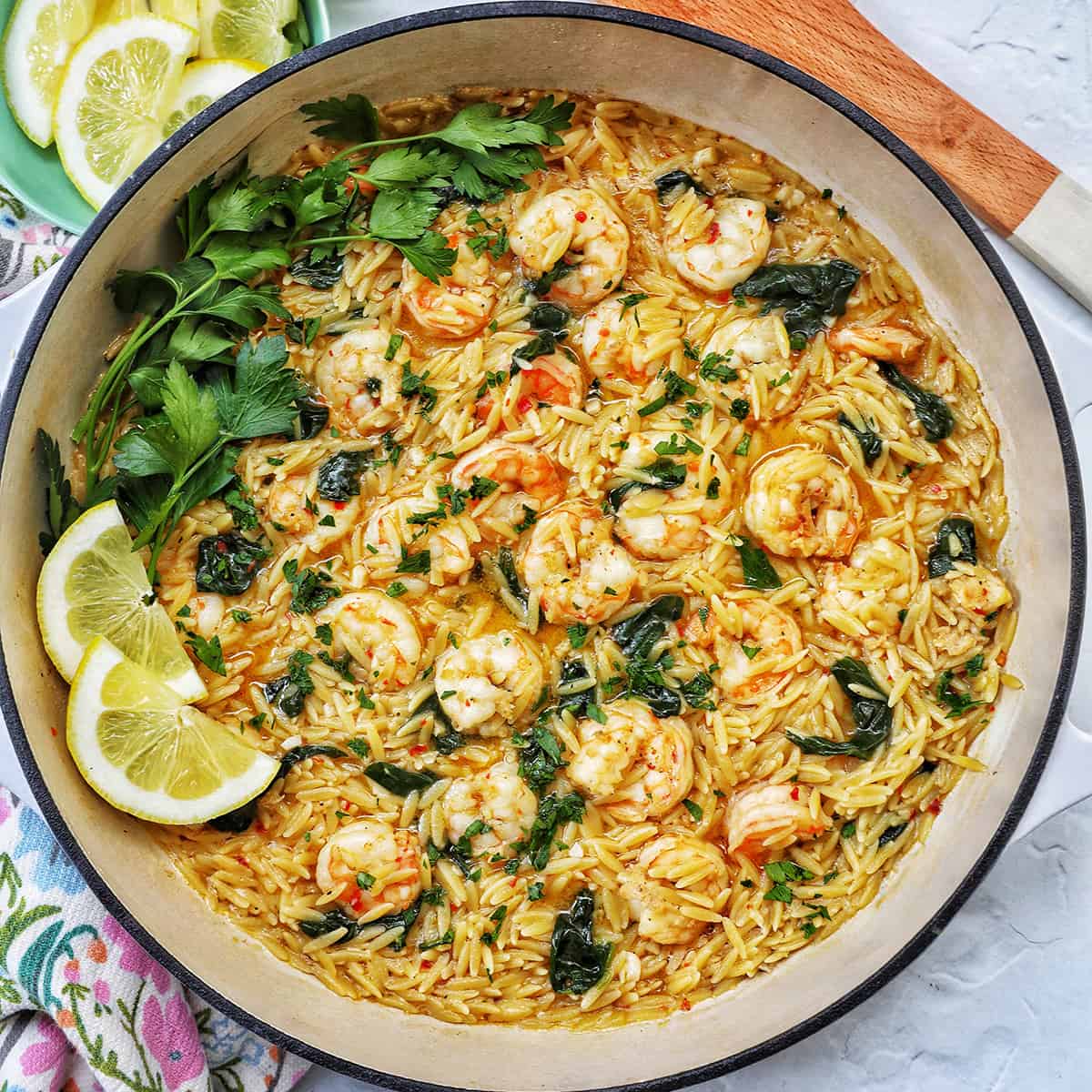 Skillet with shrimp scampi and orzo, lemons, and parsley.