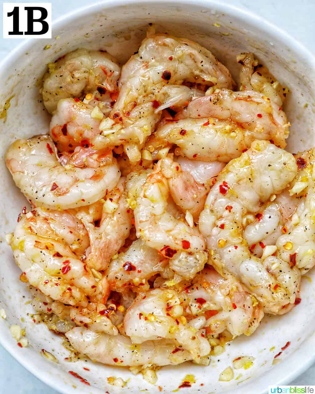 shrimp in a bowl with minced garlic and pepper flakes.