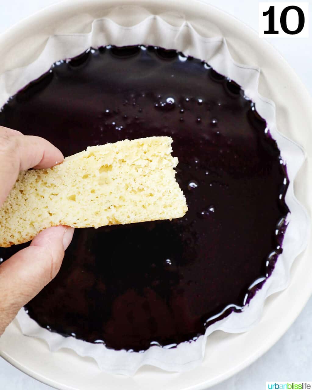 hand dipping a sponge cake bar into ube condensed milk.