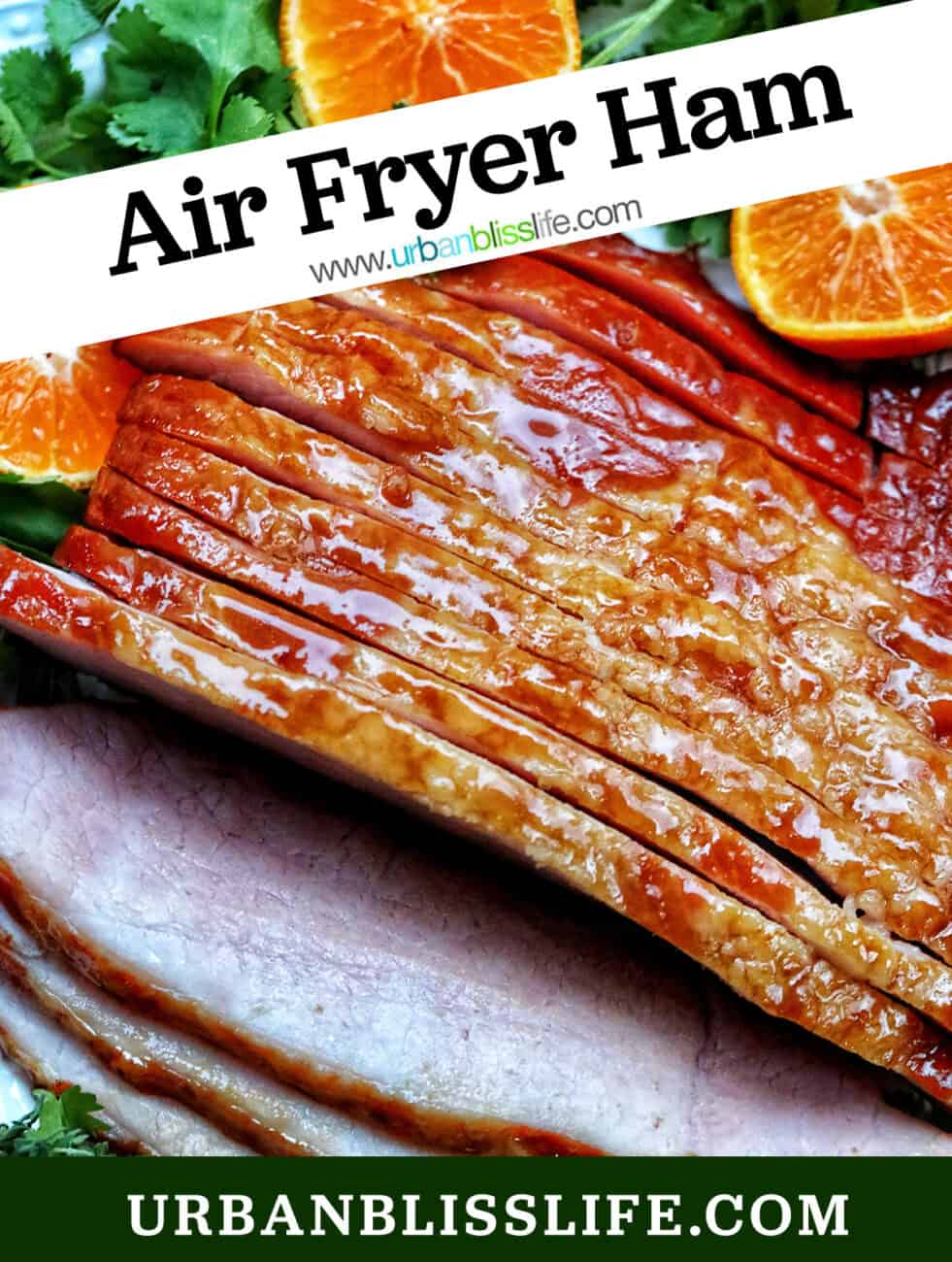 sliced honey glazed air fryer ham on a plate with fresh herbs and sliced oranges and title text overlay.