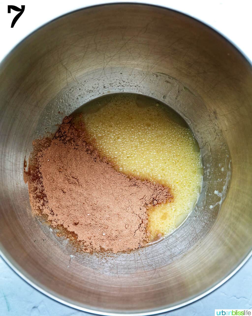 cocoa powder added to bowl of a stand mixer with wet ingredients to make chocolate fudge cupcakes.