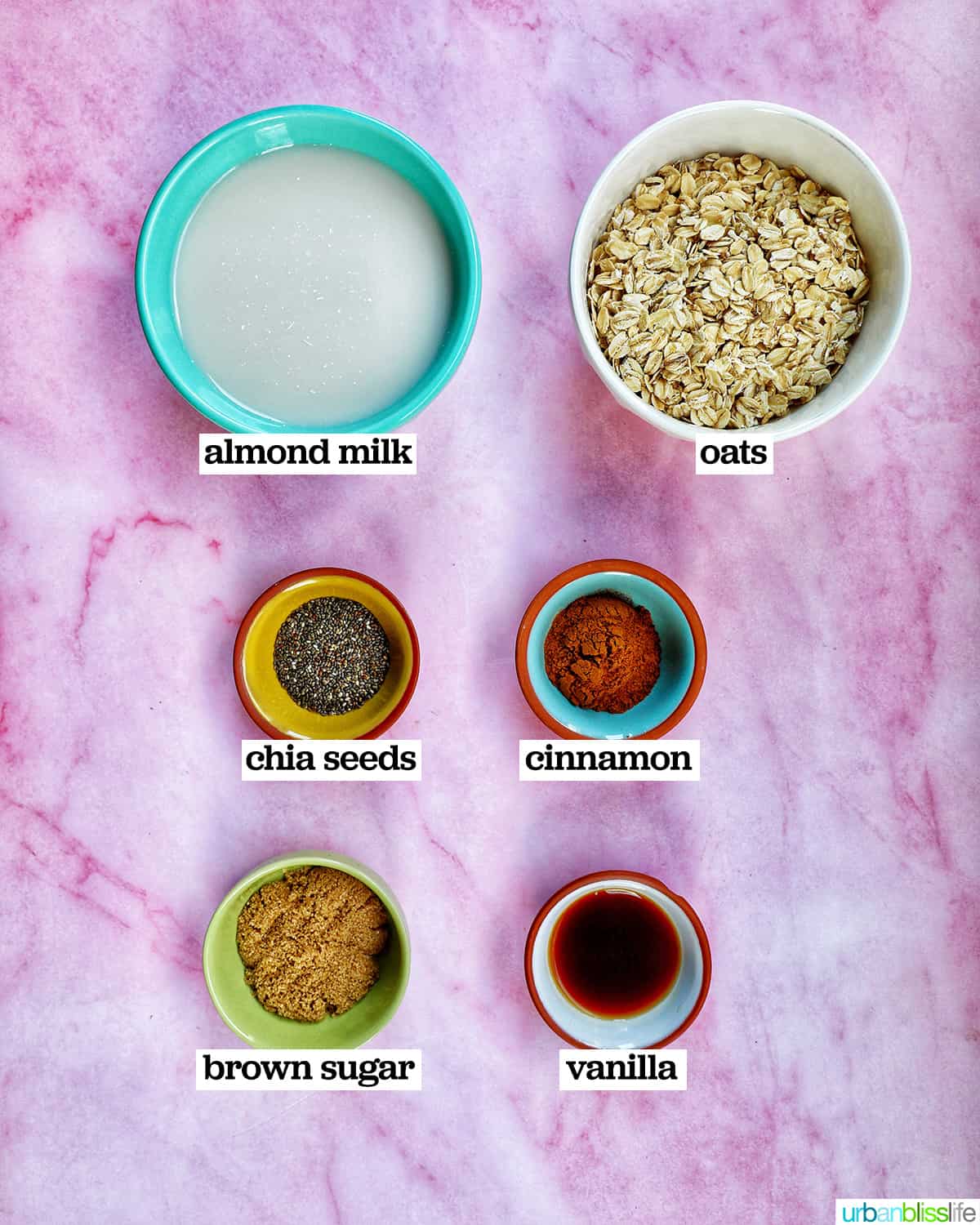 bowls of ingredients to make cinnamon roll oats on a pink board.