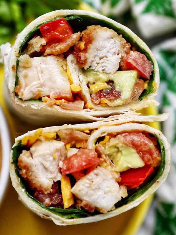honey mustard chicken wraps sliced in half with the middle exposed next to honey mustard sauce and a green and white patterned napkin.