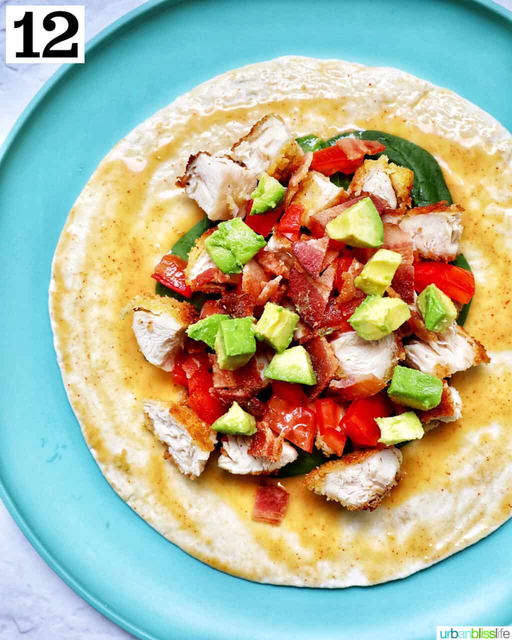 avocado, tomatoes, chicken, bacon, spinach on a tortilla wrap.