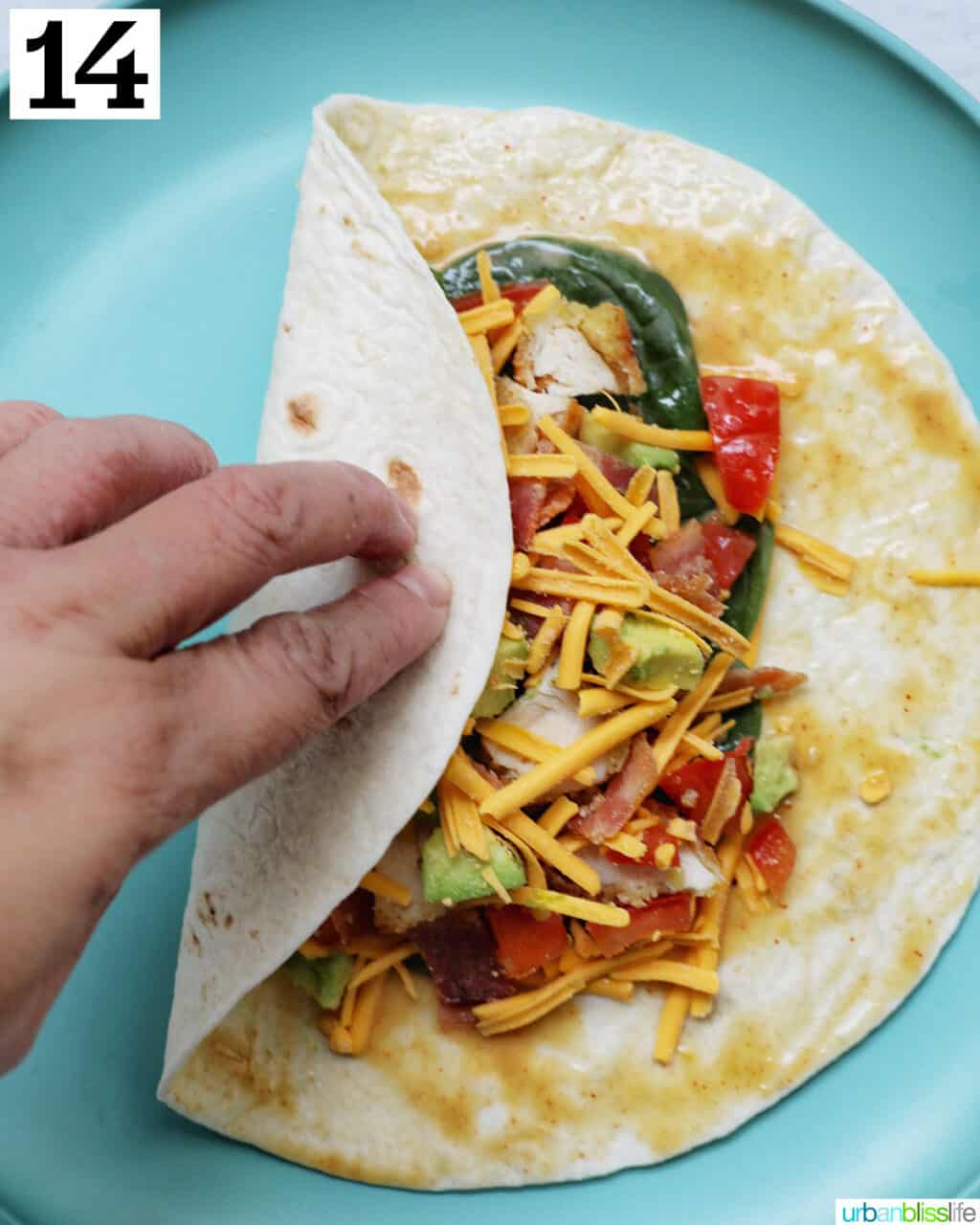 hand wrapping over one side of a tortilla over the filling.