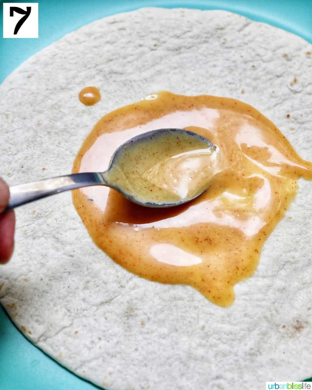 Spooning honey mustard sauce onto a tortilla.