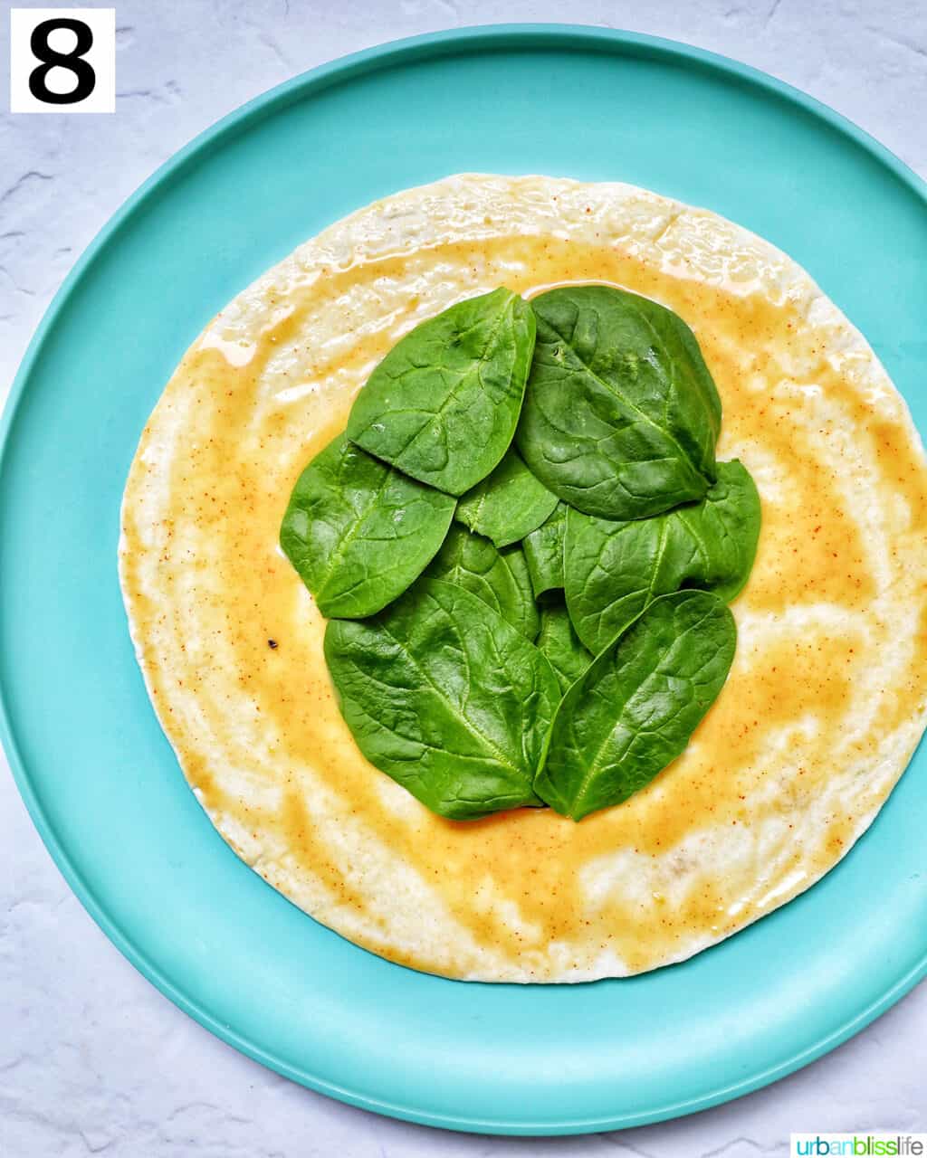 spinach added to a tortilla with honey mustard on it.
