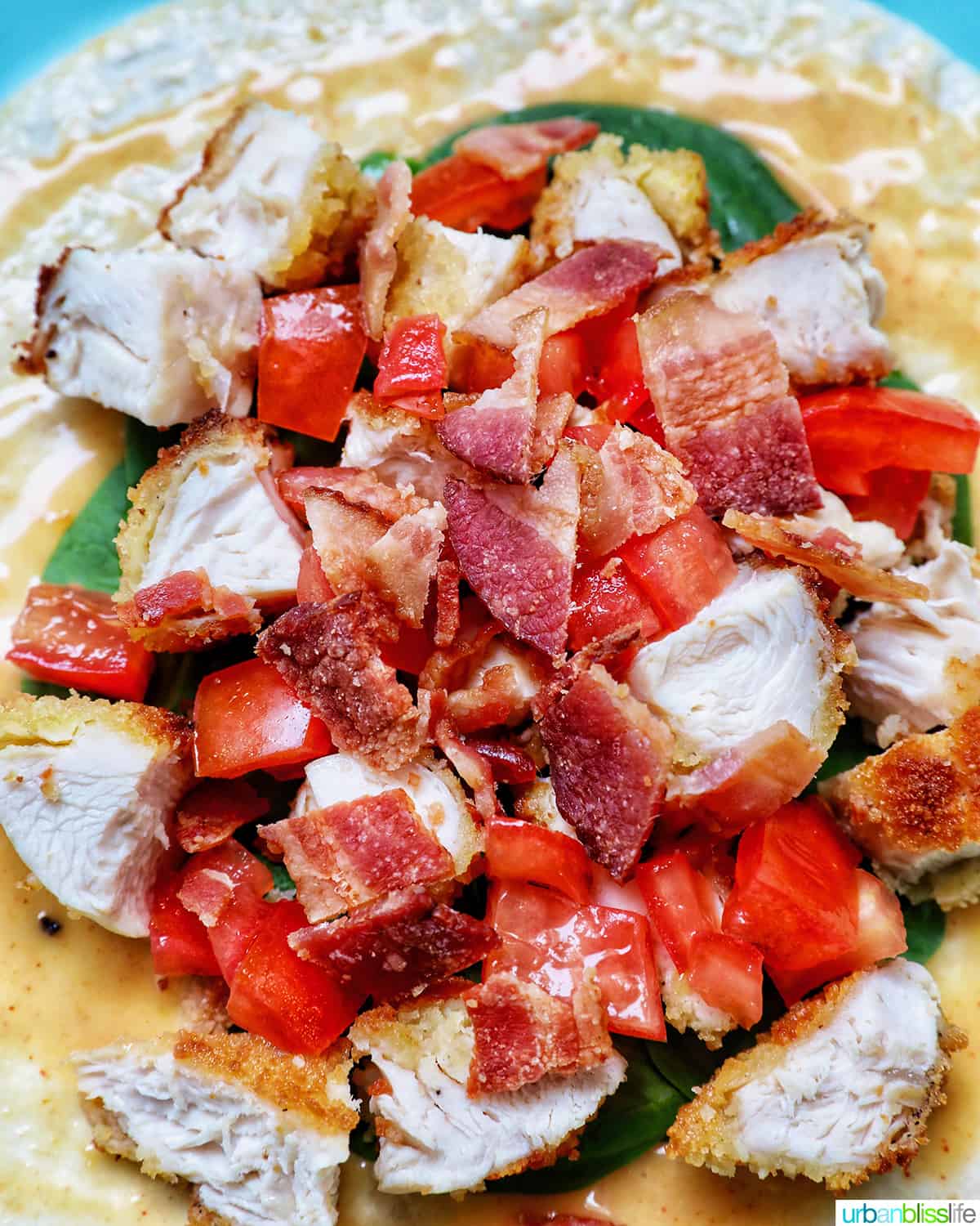 chicken, tomatoes, avocados, spinach, and bacon on a tortilla wrap.