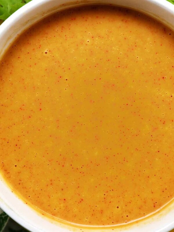 bowl of hand dipping a chicken tender into a bowl of honey mustard dipping sauce.