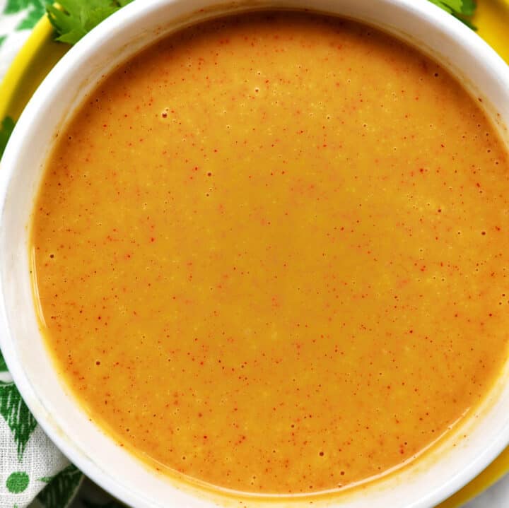 bowl of hand dipping a chicken tender into a bowl of honey mustard dipping sauce.